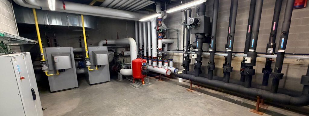 A building's plant room: gas boilers, an expansion vessel and metered heating circuits