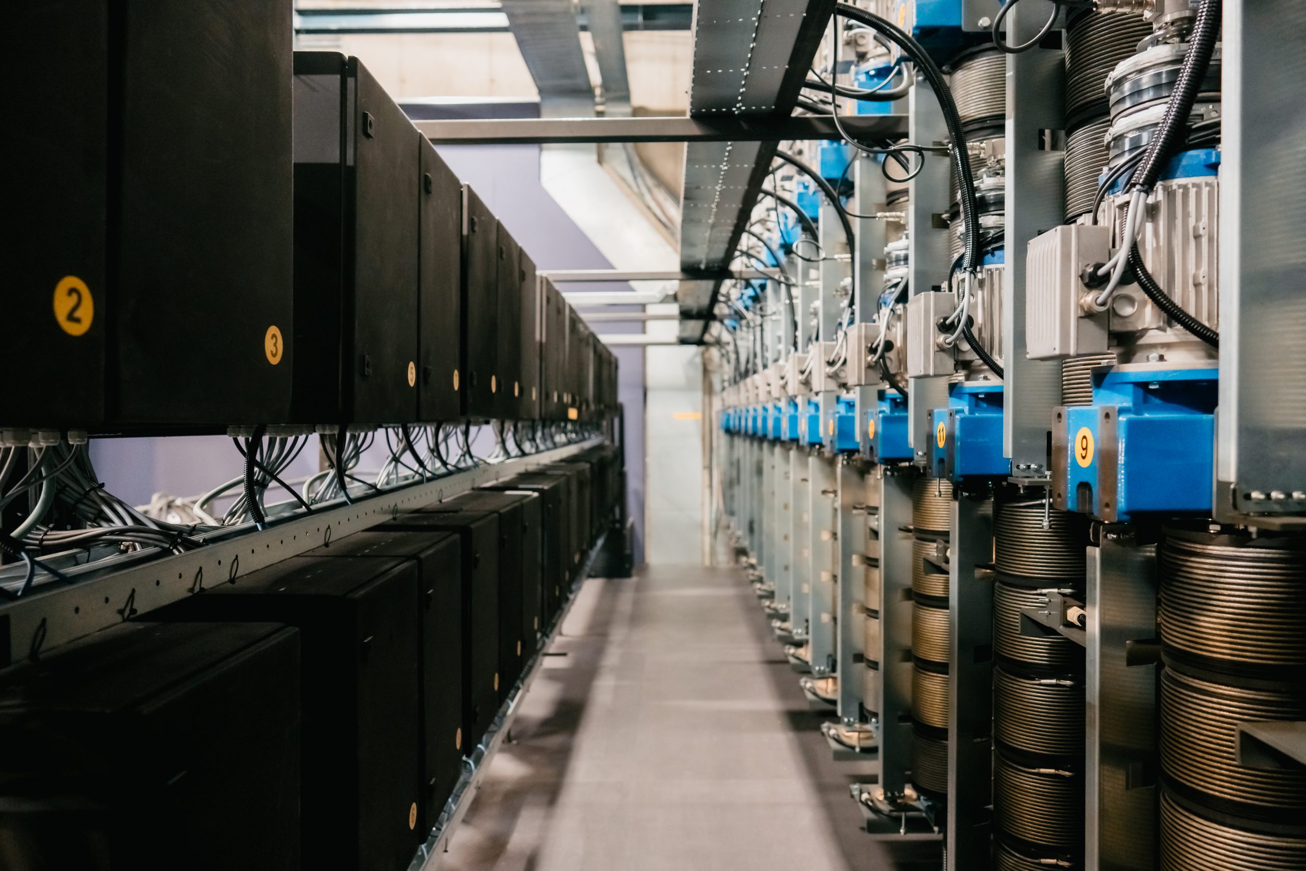 Rows of motorised rigging winches and cable drums above a stage