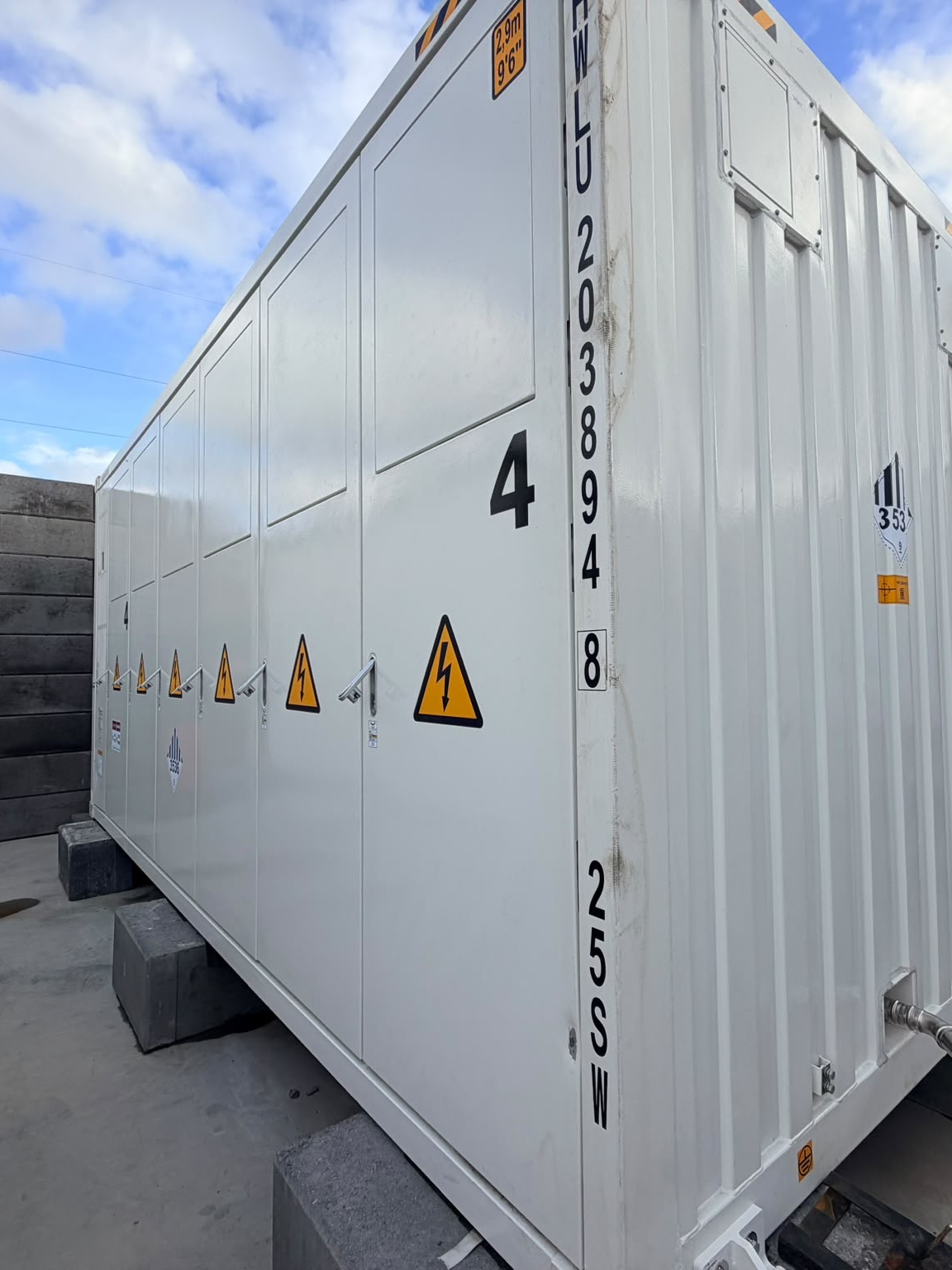 Battery system 4 at the Voltaq battery park, a white container with high-voltage warning signs